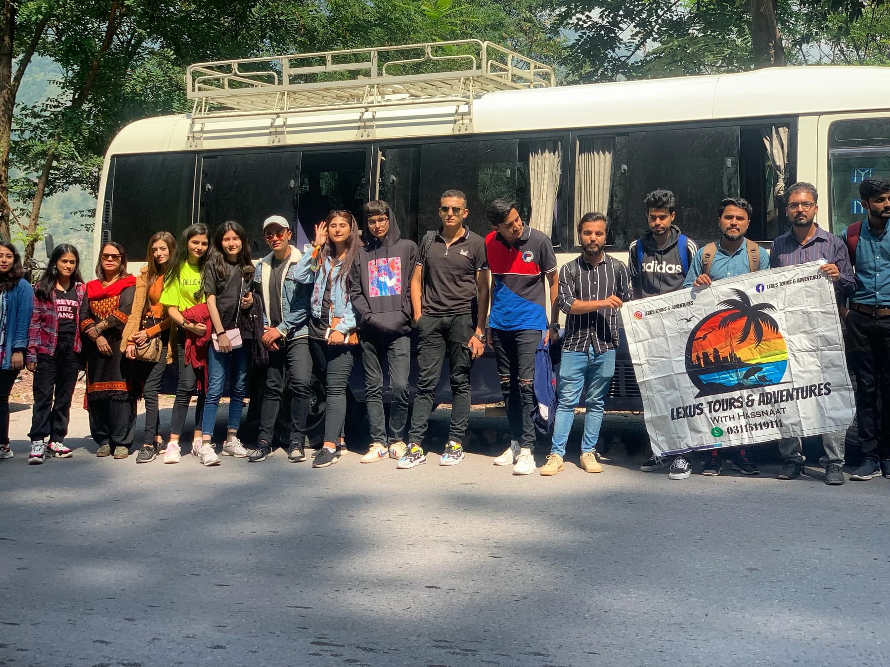 Lexuz Tours group lined up beside a branded coaster