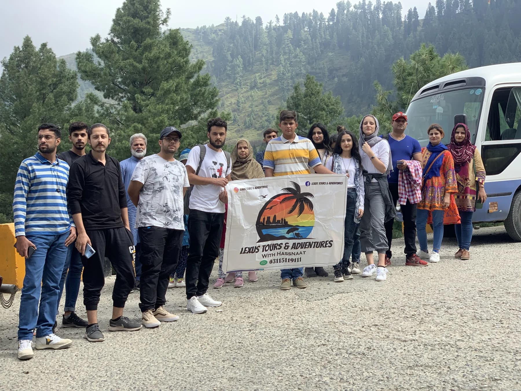 Lexuz Tours group with a banner beside a coaster in the mountains