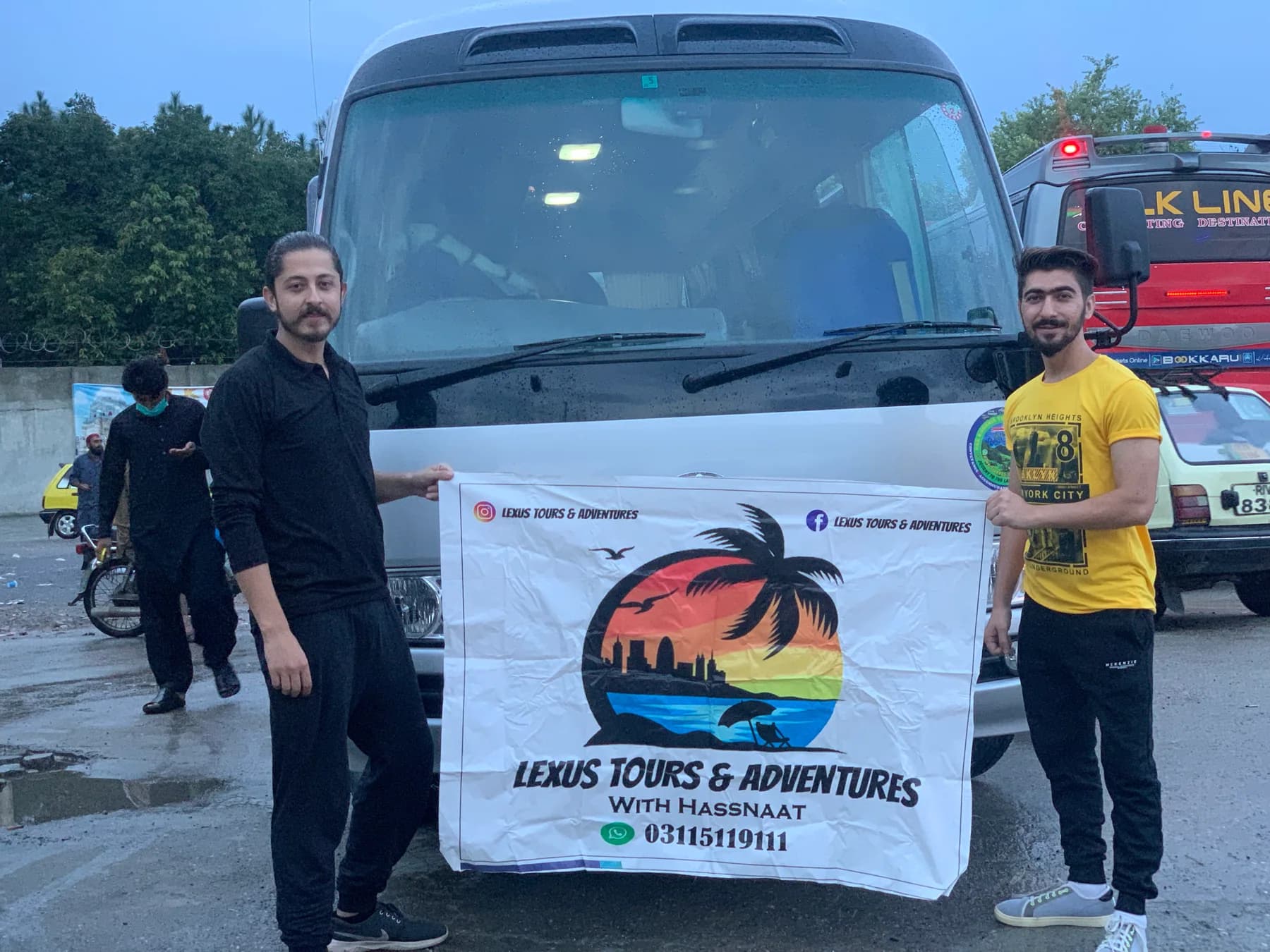 Two travellers holding a Lexuz Tours banner beside a coach