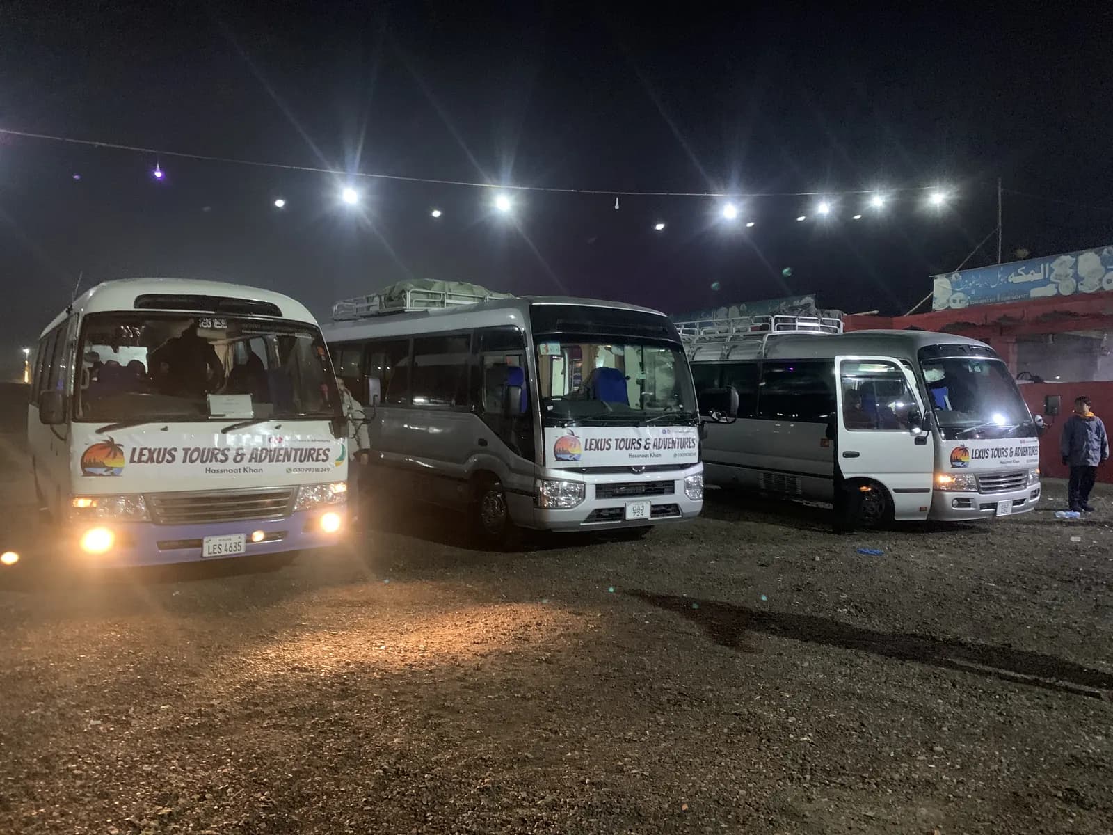 Three Lexuz Tours & Adventures branded coasters parked at night before departure